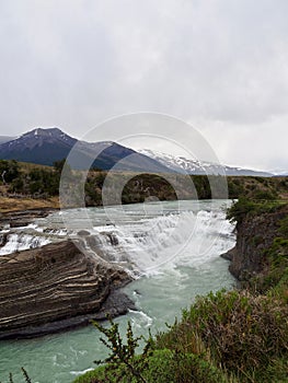 Cascada Del Rio Paine waterfall in Torres Del Paine National Park with mountains and fall fields