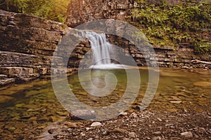 Cascade mountain waterfall with small lake in front