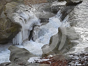 Cascade of water with white ice melting on the rock