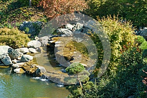 Cascade waterfall on the large lake Oike in Japanese garden. Public landscape park of Krasnodar or Galitsky Park