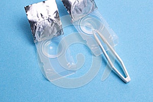 Case for daily contact lenses with tweezers on a blue textured background