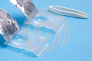 case for daily contact lenses for vision with a pair of tweezers on a blue background