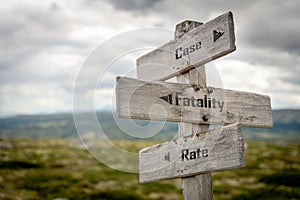 case fatality and rate text on wooden signpost outdoors in nature photo