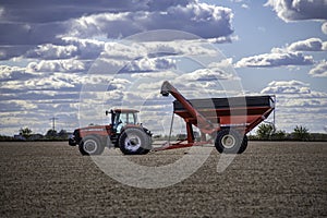 Case IH tractor and an Unverferth grain cart rest in a completely harvested field