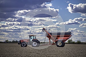 Case IH tractor and an Unverferth grain cart rest in a completely harvested field