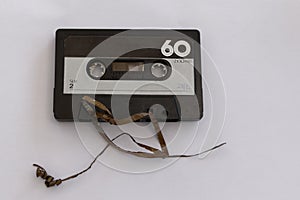 A casette tape has its broken tape going off to the left of the photo