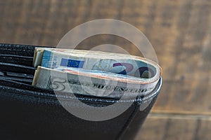 Cash American dollars and euro banknotes in a black leather wallet. Paper money closeup. The concept of payment and savings