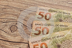 Cash bills from brazilian currency. Bils on wood rustic table.