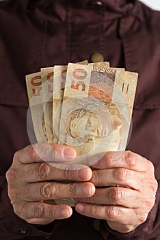 Cash bills from brazilian currency. Old retired person paying in cash