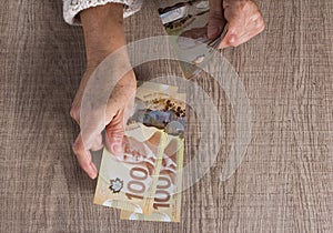 Cash bills from Canadian currency. Dollars. Above view of old retired person paying in cash