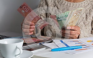 Cash bills from Canadian currency. Dollars. Old woman counting bills on table