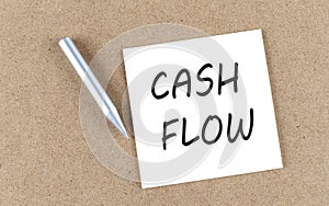 CASH FLOW text on sticky note on a cork board with pencil