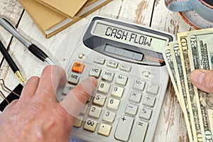 CASH FLOW - words on calculator.Money in hand and office supplies