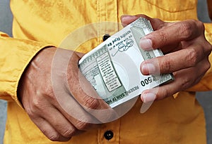 Cash in hand or money in hand holding Indian currency 500 rupee note