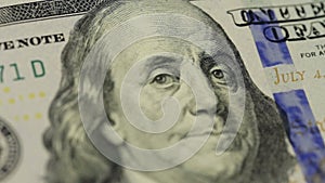 Cash money background. Benjamin Franklin portrait on 100 US dollar bill close up, the image is rotated