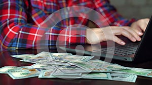 Cash money falling on table of employee using laptop in office