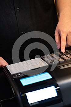 cash register installed on counter for accepting order from customer.sales man entering amount on electronic cash register in