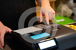 cash register installed on counter for accepting order from customer.sales man entering amount on electronic cash register in