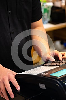 cash register installed on counter for accepting order from customer.sales man entering amount on electronic cash register in