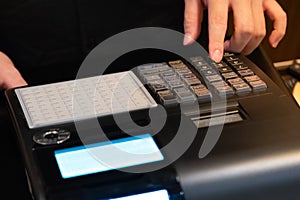 cash register installed on counter for accepting order from customer.sales man entering amount on electronic cash register in