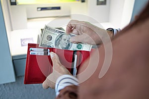 Cash withdrawal from ATM. Unrecognizable female holding in hands wallet with dollars money.