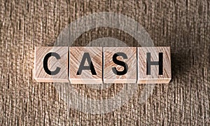 Cash - word written on wooden blocks on a brown background