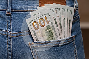Cash in your pocket. A hundred dollar bills stuck out of the back pocket of blue jeans. Money saving concept