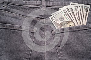 Cash in your pocket. A hundred dollar bills stuck out of the back pocket of grey jeans. Money saving concept
