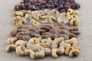 Cashew, almonds, walnuts and hazelnuts on a burlap fabric. Selective focus.