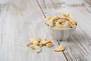 Cashew nuts in the white bowl on wood table