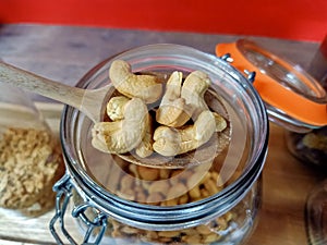 Cashew in a wooden spoon on a clear glass jar.