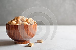 Cashews in a brown wooden bowl on a gray background with a copy of the space