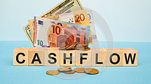CASHFLOW - word written on wood cubes on the background of various banknotes