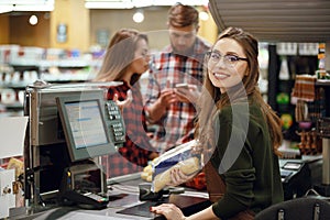 Cashier woman on workspace in supermarket shop.