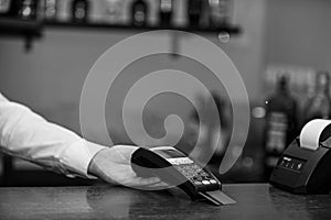 Cashiers hand holds credit card reader on defocused background