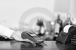 Cashiers hand holds credit card reader on light defocused background.