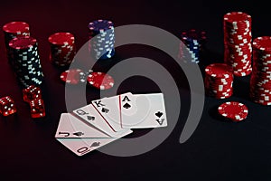 Casino chips and cards on black table surface. Gambling, fortune, game and entertainment concept - close up