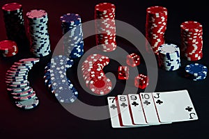 Casino chips and cards on black table surface. Gambling, fortune, game and entertainment concept - close up