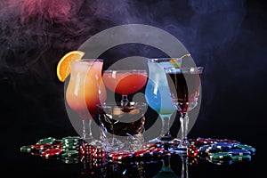 Casino chips, dice and alcohol drinks on dark background with smoke