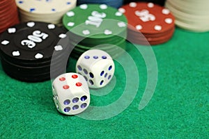 Casino chips and dice on a green felt table, selective focus