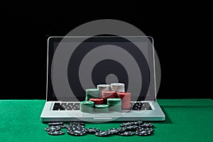 Casino chips on keyboard notebook at green table.