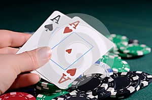 Casino chips and pair of aces in a woman's hand. Poker game concept