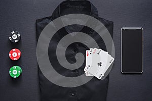Casino chips, playing cards on formal shirt and mobile phone. set of four aces