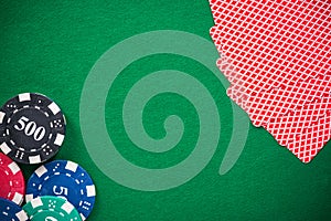 Casino chips and poker cards on green felt, background