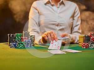 Casino. The croupier is holding playing cards and there are a lot of chips next to him. Gaming green table. Risk, luck, pastime.