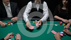 Casino dealer shuffling and distributing cards, players checking combination