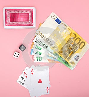 Casino, gambling and fortune concept. Game bones and cards and euro money on pink background with copy space