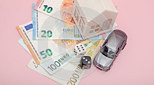 Casino, gambling and fortune concept. Model house and car, games dice and euro money on pink background with copy space