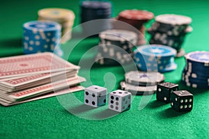 Casino, gambling. Poker chips piles, playing cards and dice on green felt background