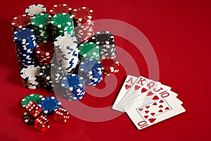 Casino gambling poker equipment and entertainment concept - close up of playing cards and chips at red background. Royal